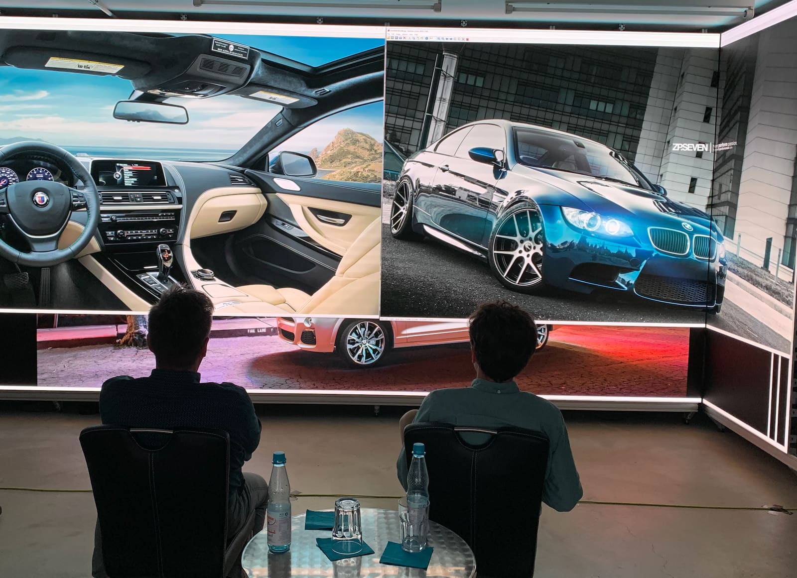 Two viewers seated in front of a large curved TRUE dvLED wall showing BMW design imagery