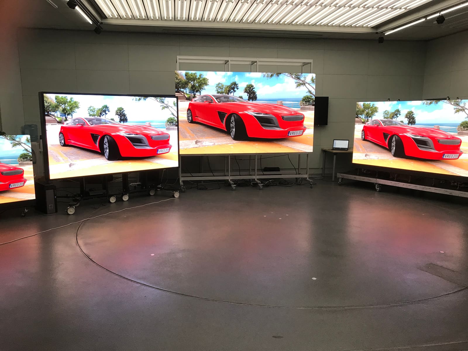 Three rolling TRUE dvLED demo walls showing a red concept car in the lab showroom