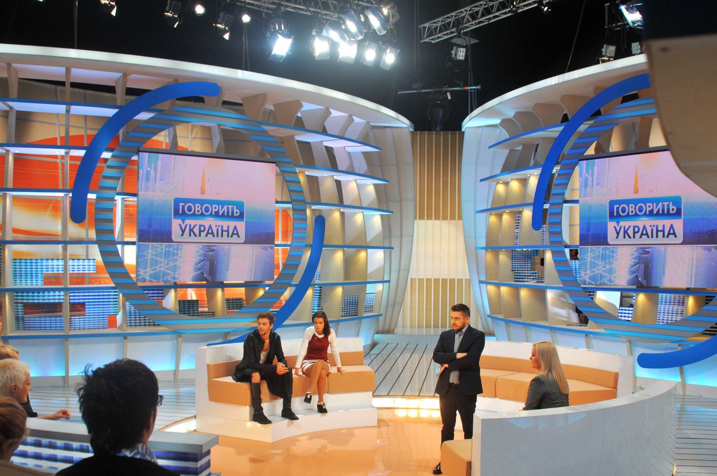 Daylight talk studio with blue and white curved TRUE dvLED shelving behind four guests