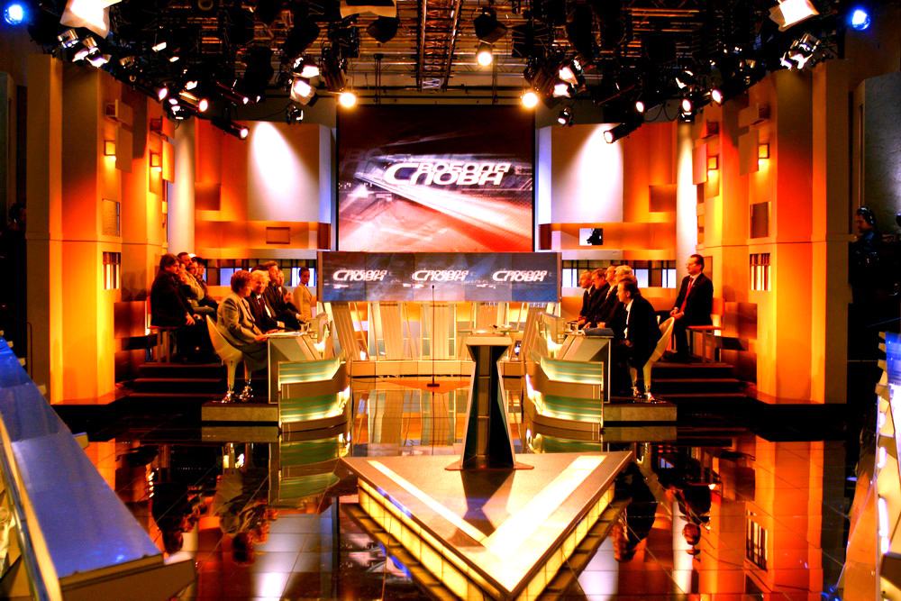 Amber lit talk studio with a panel of guests and a symmetric TRUE dvLED wedge