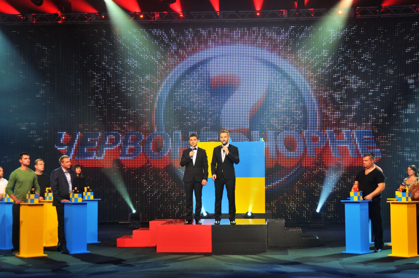 Flag coloured TRUE dvLED wall behind hosts and contestants on a frontal stage