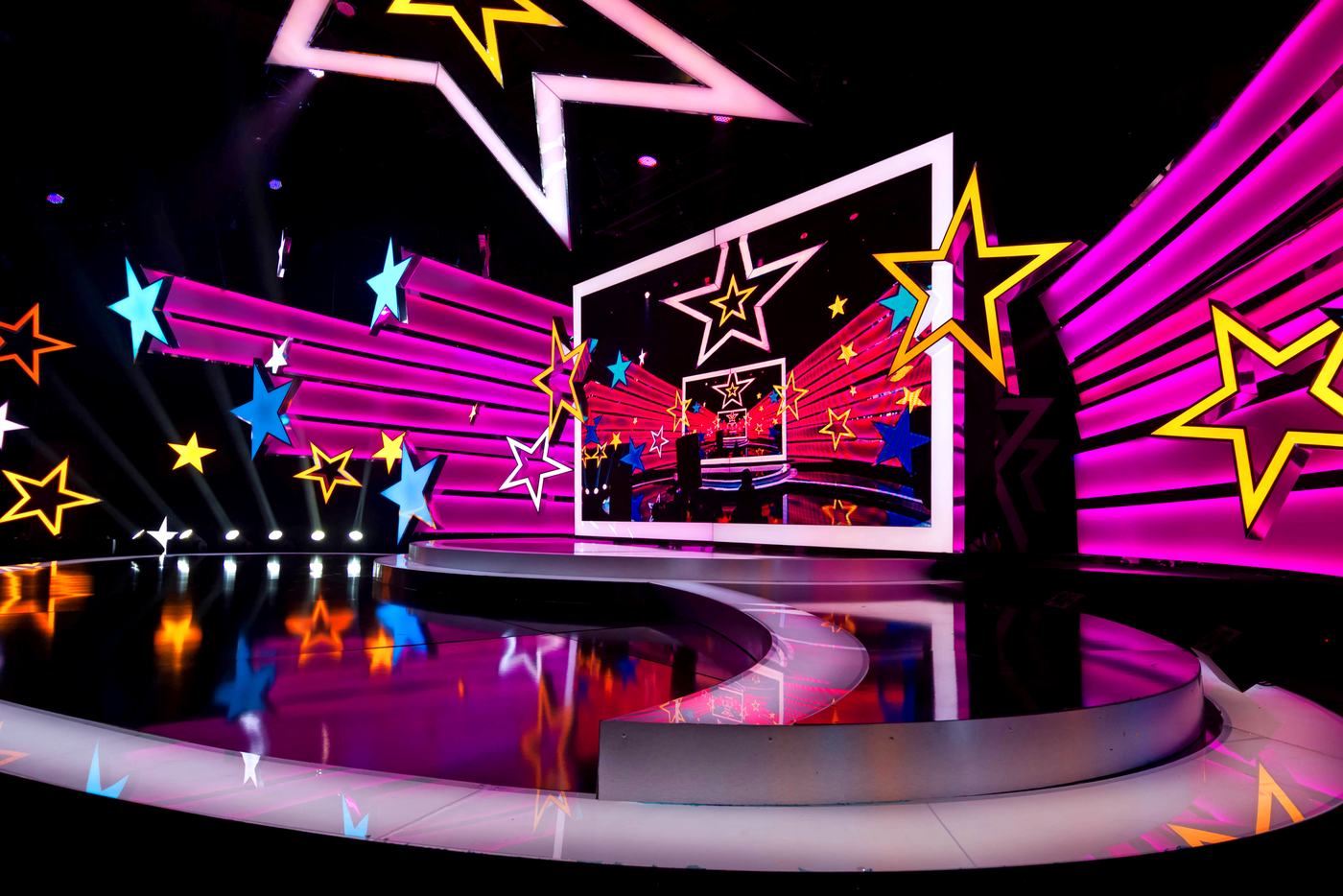 Empty curved stage with a magenta and cyan star graphic across TRUE dvLED