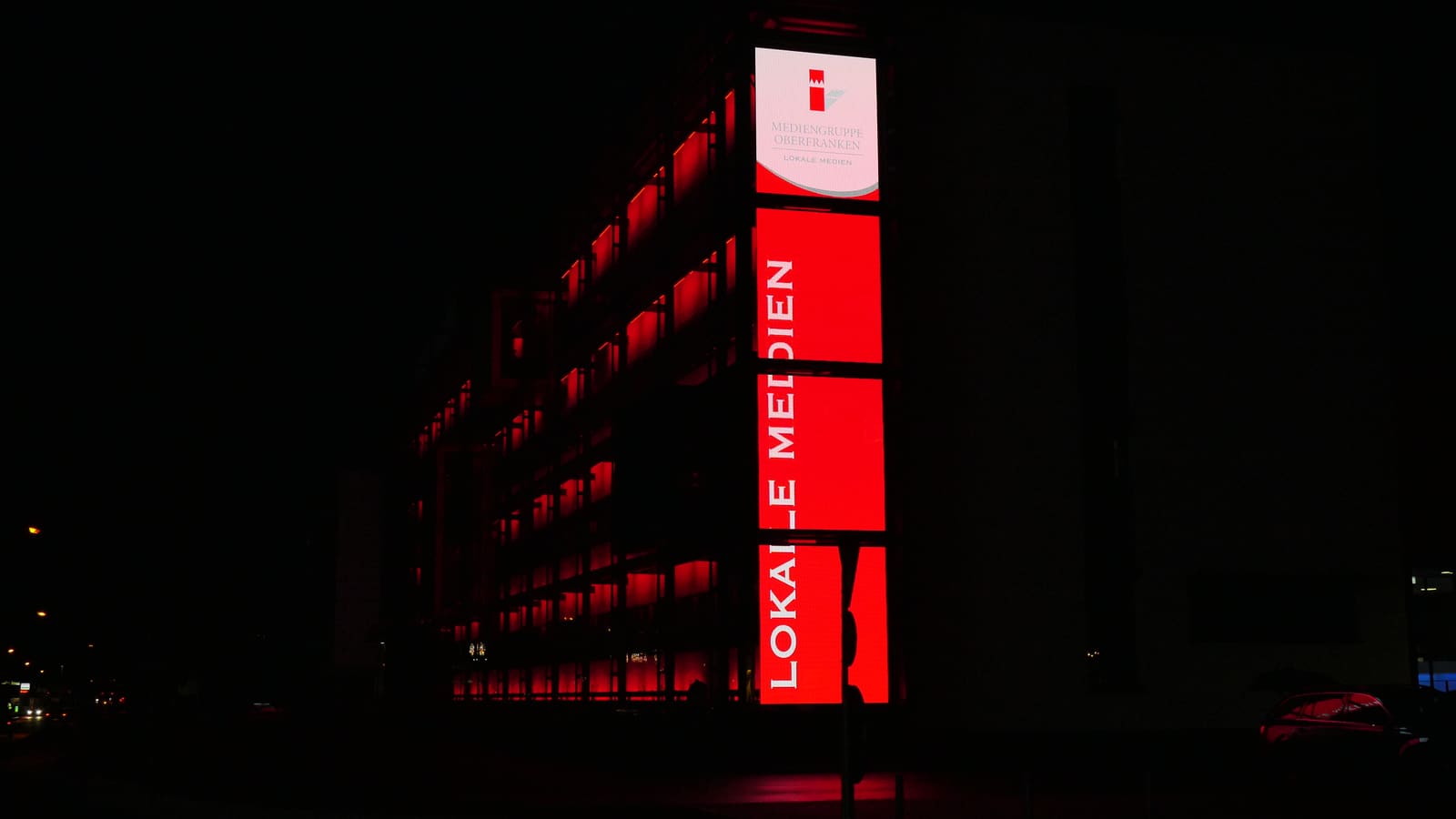 Red lit TRUE dvLED facade columns carrying local media content at night