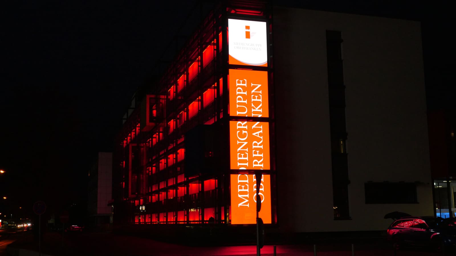 Glowing TRUE dvLED media facade on a building corner at night
