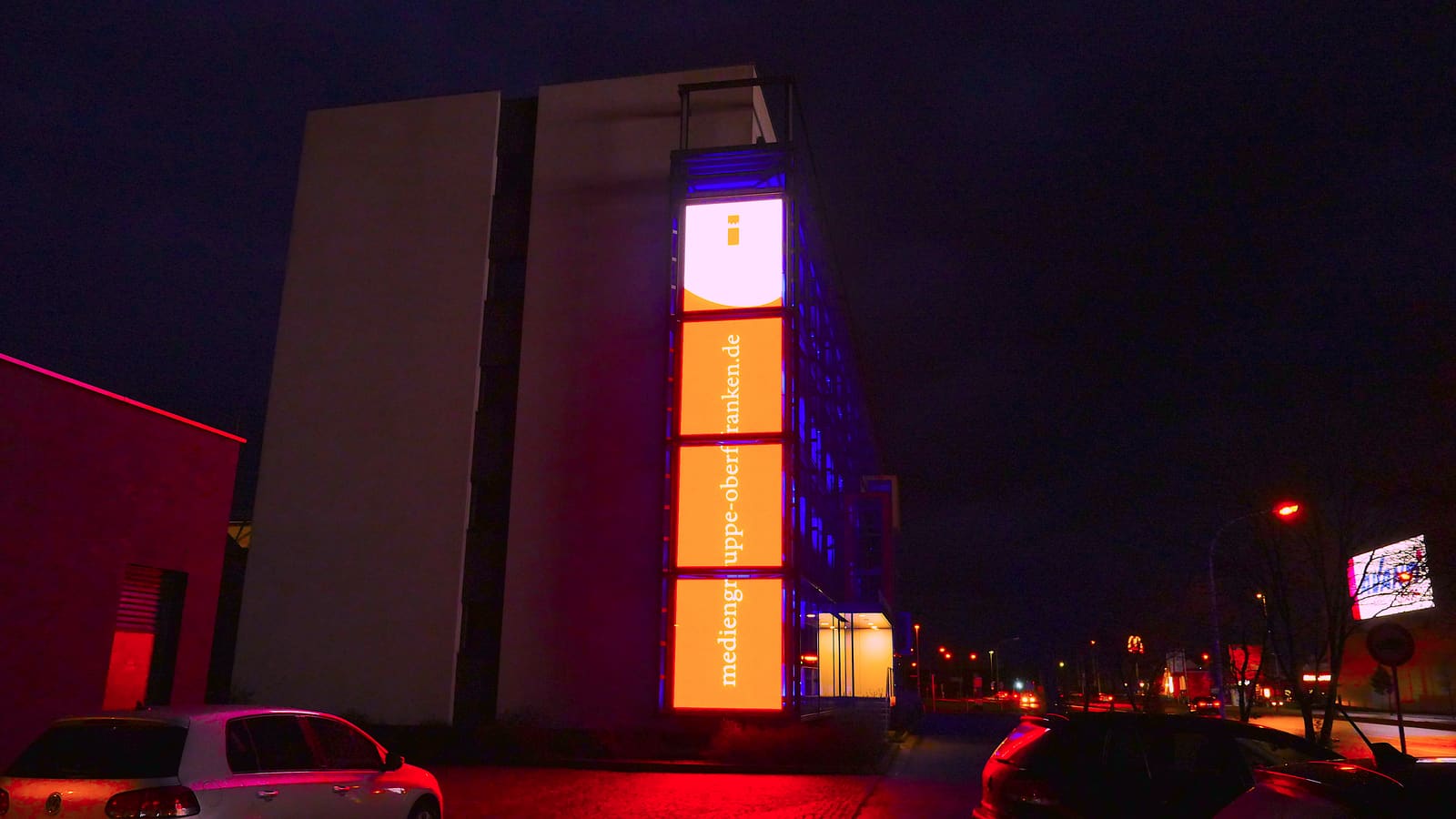 Tall TRUE dvLED column on a building facade lit orange at night