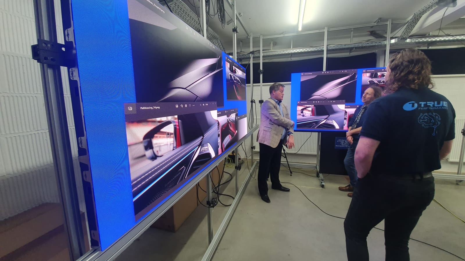 TRUE staff presenting car renders on the lab wall to visitors
