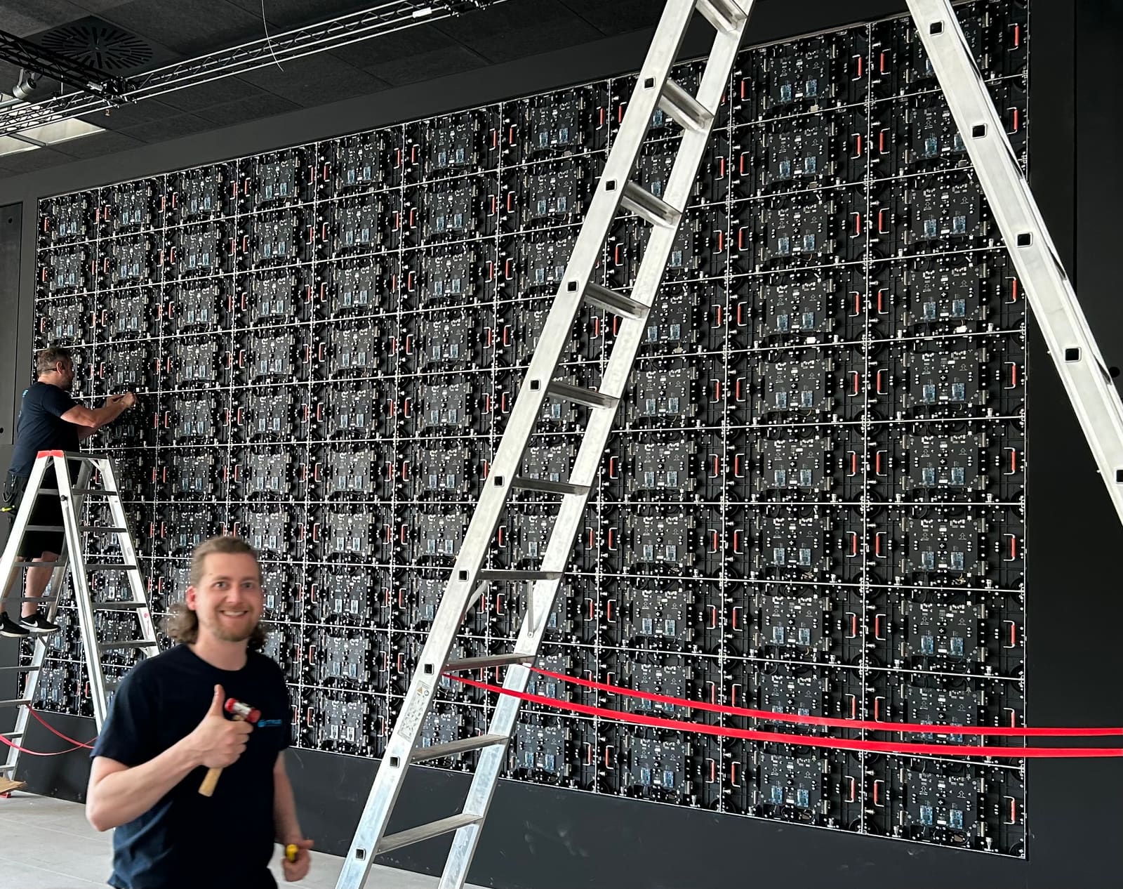 Technicians on ladders mounting TRUE dvLED cabinets during an installation
