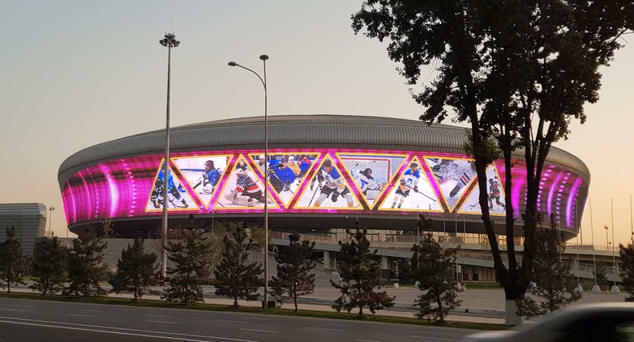 Arena facade wrapped in TRUE dvLED at dusk, showing live ice hockey around the whole building