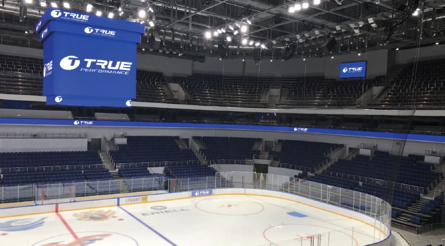 Empty ice hockey arena with a TRUE branded center hung dvLED cube and ribbon boards