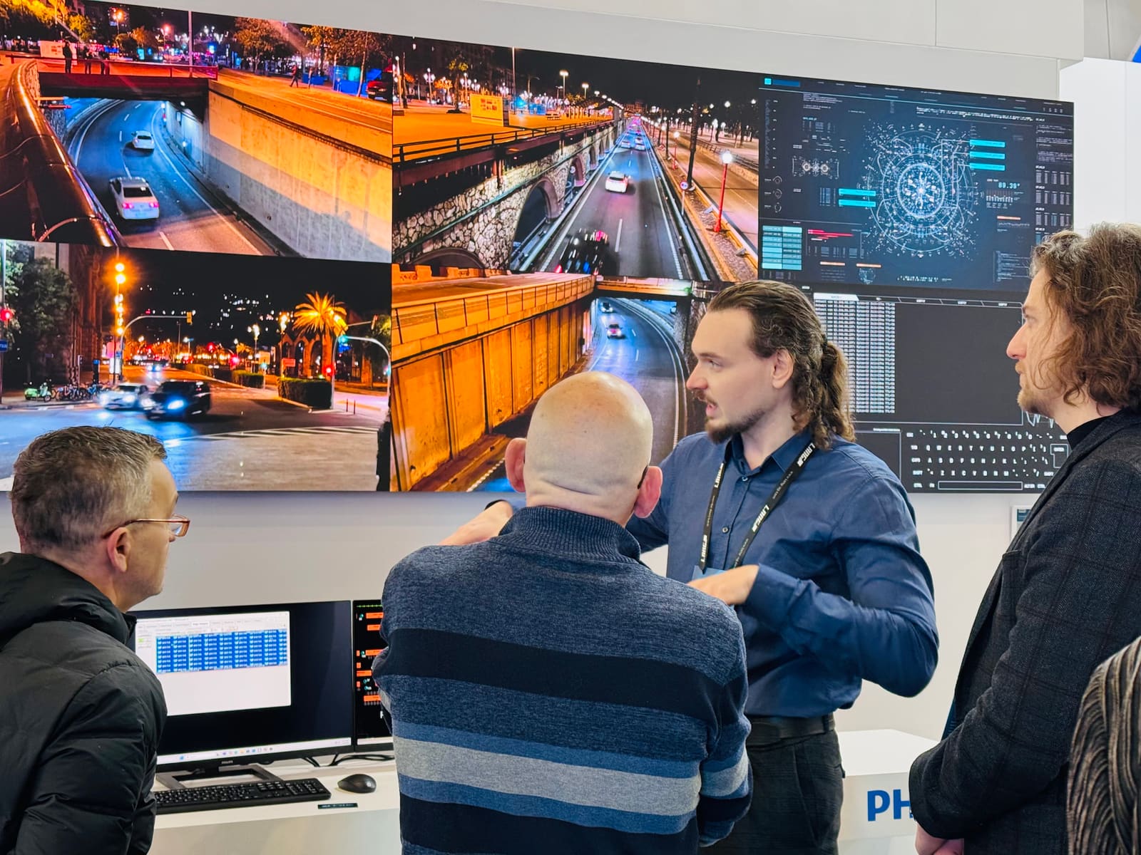 Four people talking in front of a TRUE dvLED video wall showing night traffic camera feeds