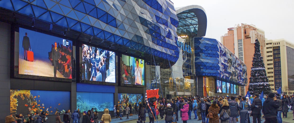 Shopping mall facade with several TRUE dvLED screens above a winter crowd and a Christmas tree