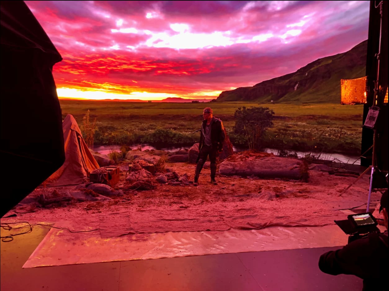 Virtual production volume showing a red sunset landscape behind an actor on a sand covered set